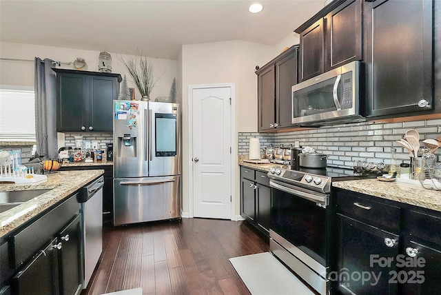 kitchen with dark hardwood / wood-style floors, appliances with stainless steel finishes, backsplash, and light stone counters