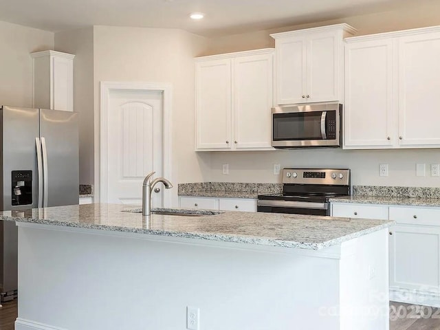 kitchen with sink, white cabinets, appliances with stainless steel finishes, and an island with sink