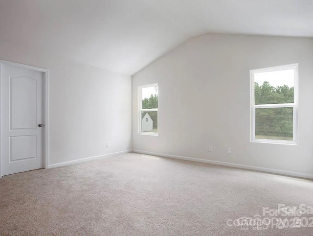 unfurnished room featuring light carpet and lofted ceiling