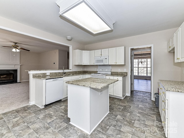 kitchen featuring ceiling fan, a kitchen island, sink, white appliances, and white cabinets