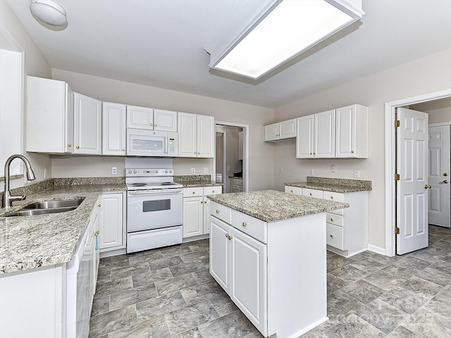 kitchen featuring light stone countertops, white appliances, a center island, white cabinetry, and sink