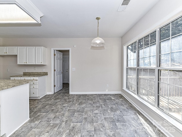 kitchen with pendant lighting, white cabinets, and a healthy amount of sunlight