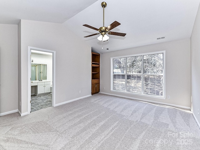 unfurnished bedroom featuring ceiling fan, light carpet, ensuite bathroom, and lofted ceiling