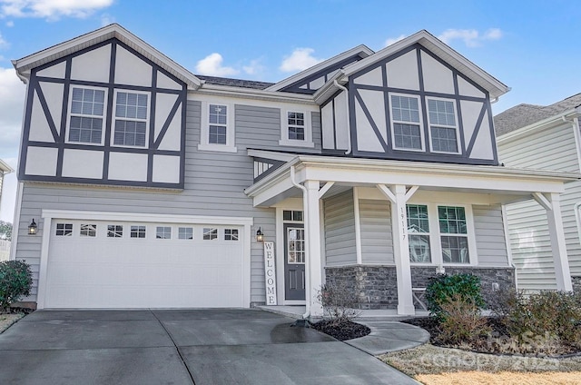 tudor house featuring stone siding, driveway, and a garage