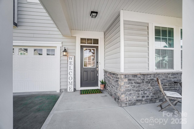 view of exterior entry with stone siding and a garage