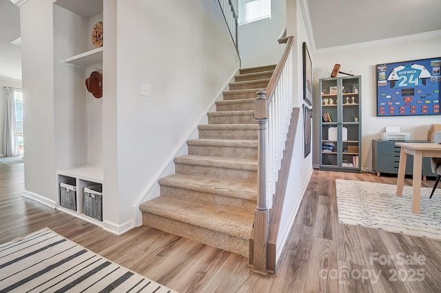 stairway with ornamental molding and wood-type flooring