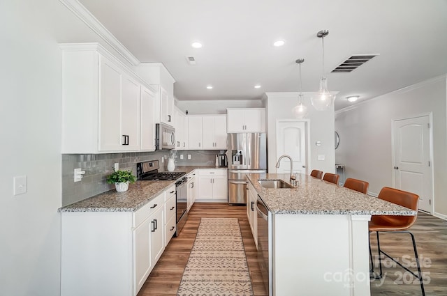 kitchen with a sink, wood finished floors, appliances with stainless steel finishes, and a breakfast bar area