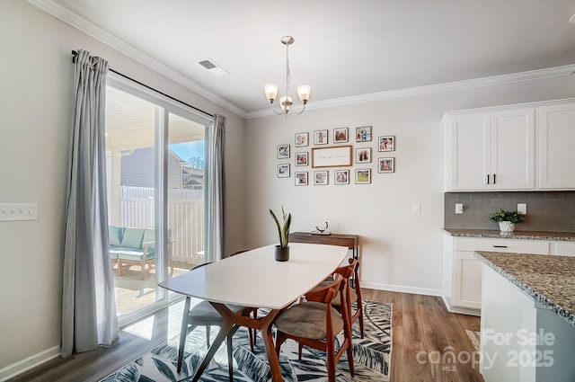 dining space featuring a chandelier, baseboards, light wood finished floors, and ornamental molding