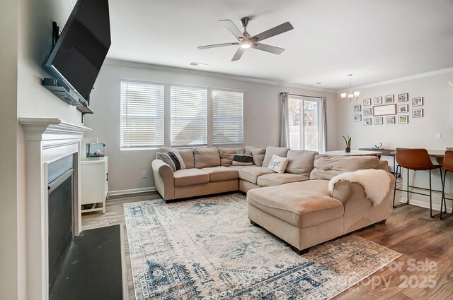 living room with hardwood / wood-style flooring, crown molding, and ceiling fan with notable chandelier