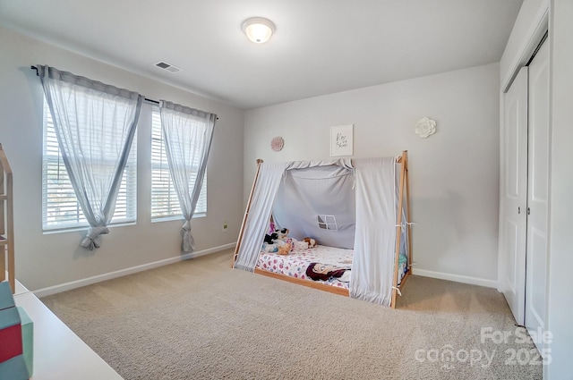 carpeted bedroom featuring baseboards, visible vents, and a closet