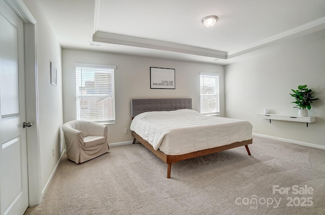 carpeted bedroom with a tray ceiling and ornamental molding