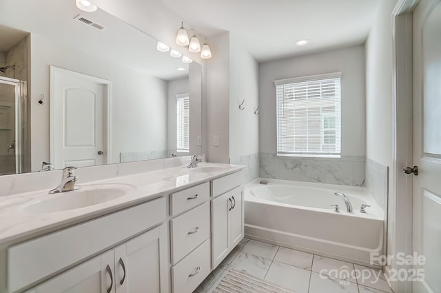 bathroom featuring vanity, plus walk in shower, and a wealth of natural light