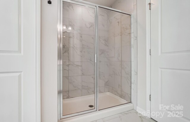 bathroom with marble finish floor and a stall shower