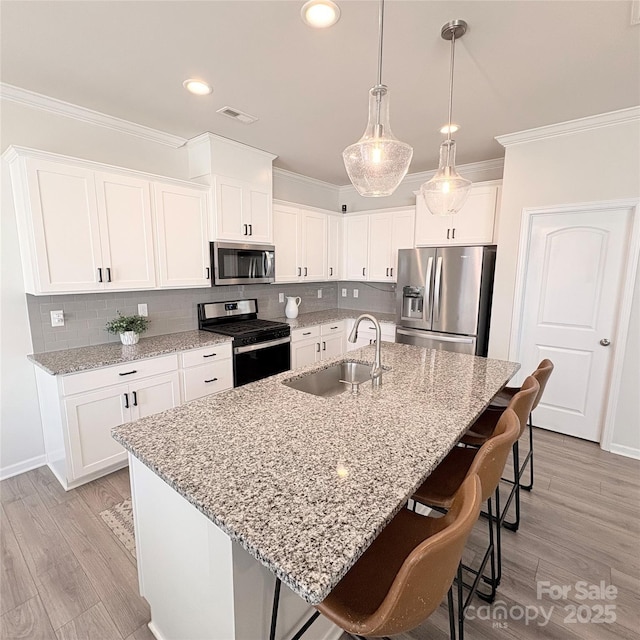 kitchen featuring a sink, tasteful backsplash, stainless steel appliances, a breakfast bar area, and crown molding