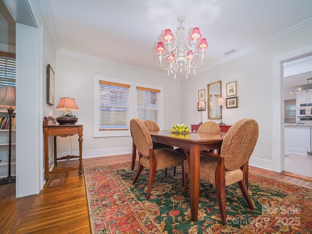 dining area featuring a notable chandelier, crown molding, and hardwood / wood-style flooring