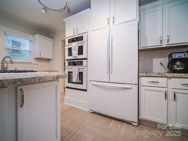 kitchen featuring tasteful backsplash, white appliances, crown molding, white cabinets, and sink