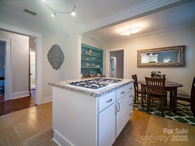 kitchen featuring white cabinets, a kitchen island, light parquet flooring, ornamental molding, and gas cooktop