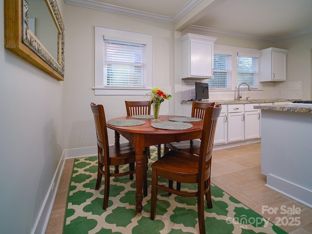 dining space with a wealth of natural light, crown molding, and light hardwood / wood-style flooring