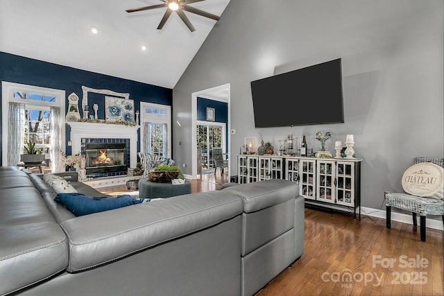 living room featuring a healthy amount of sunlight, dark hardwood / wood-style flooring, high vaulted ceiling, and a tile fireplace