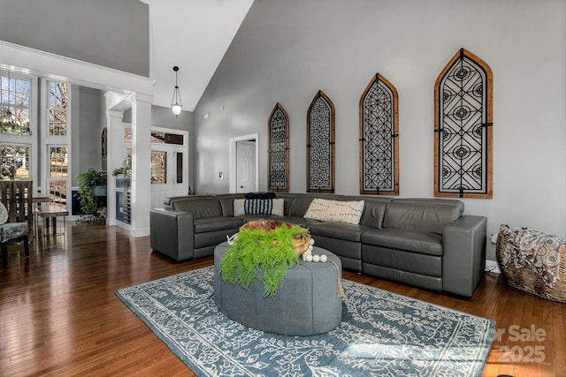 living room with a towering ceiling and dark wood-type flooring