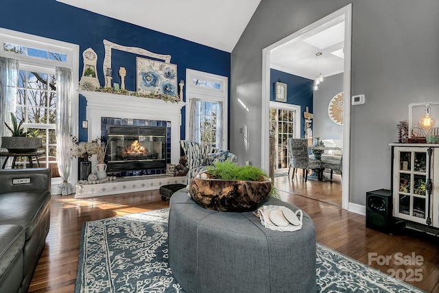 living room featuring a tiled fireplace, vaulted ceiling, and hardwood / wood-style floors