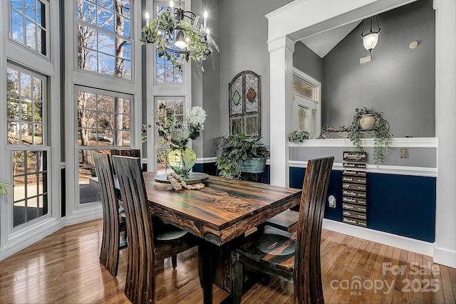 dining space featuring an inviting chandelier, a towering ceiling, and hardwood / wood-style floors