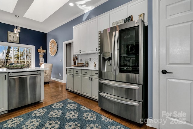 kitchen with a skylight, stainless steel appliances, white cabinets, dark hardwood / wood-style flooring, and decorative light fixtures