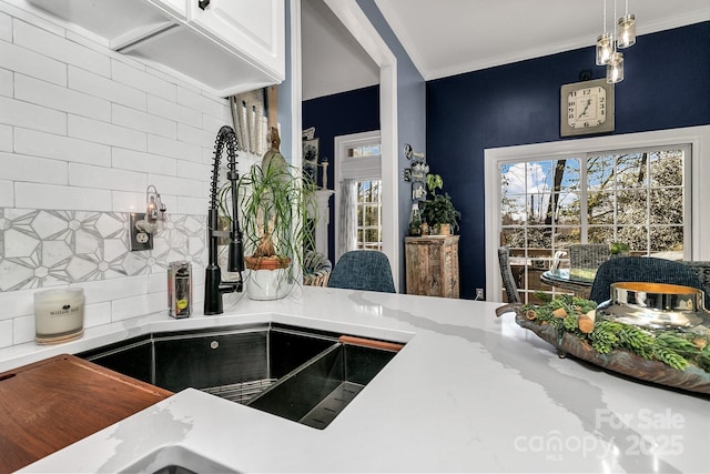 room details with crown molding, sink, pendant lighting, and backsplash