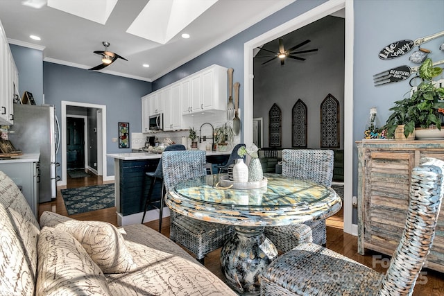 dining room with a skylight, sink, dark hardwood / wood-style flooring, ceiling fan, and crown molding