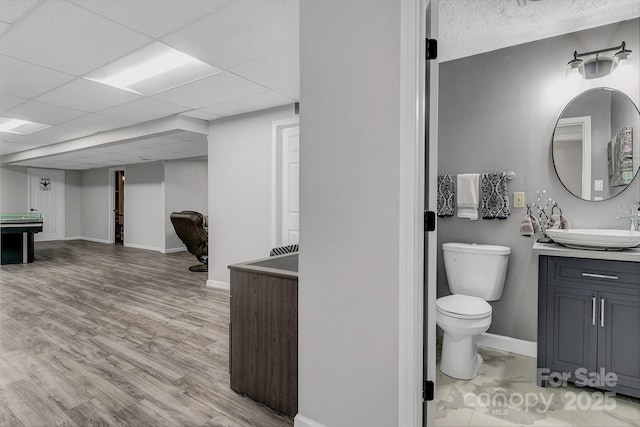 interior space with hardwood / wood-style flooring, a paneled ceiling, vanity, and toilet