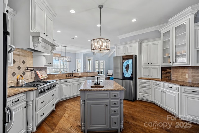 kitchen with appliances with stainless steel finishes, decorative light fixtures, white cabinetry, a center island, and light stone countertops