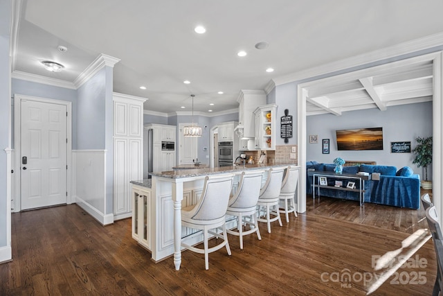 kitchen featuring a breakfast bar area, white cabinetry, dark hardwood / wood-style floors, kitchen peninsula, and light stone countertops