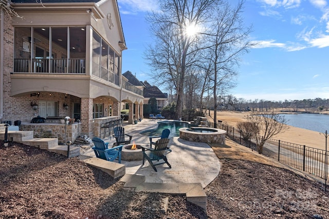 view of patio / terrace with a water view, an outdoor fire pit, a swimming pool with hot tub, exterior bar, and a sunroom