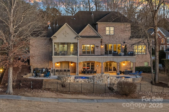 back house at dusk with a patio, a balcony, and area for grilling