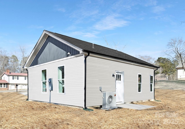 rear view of house with ac unit and a yard