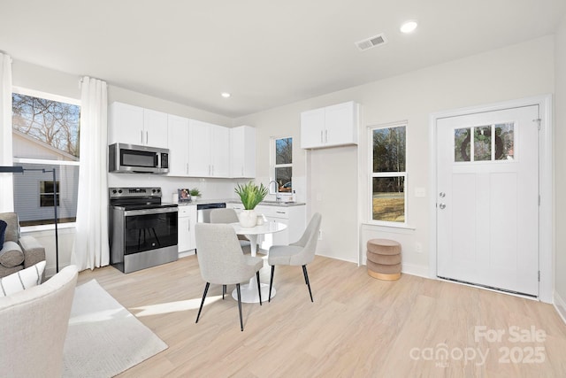 kitchen featuring white cabinetry, sink, stainless steel appliances, and light wood-type flooring