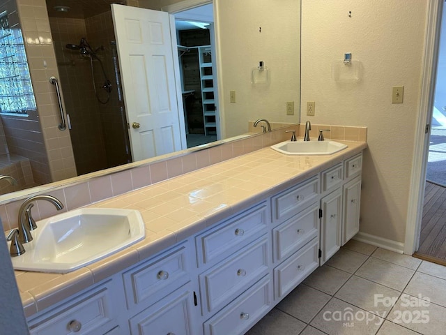 bathroom with a shower with door, tile patterned floors, and vanity