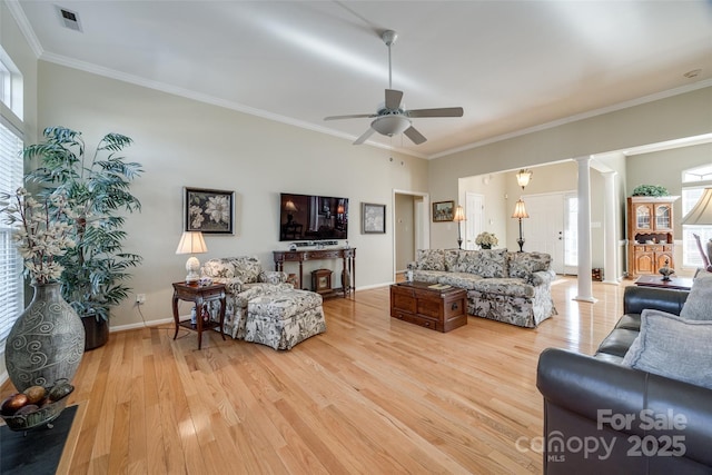 living room with decorative columns, crown molding, ceiling fan, and light wood-type flooring