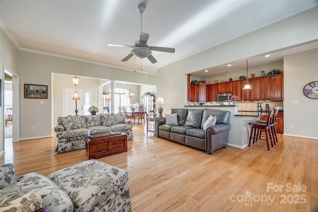 living room featuring ceiling fan with notable chandelier, crown molding, and light wood-type flooring