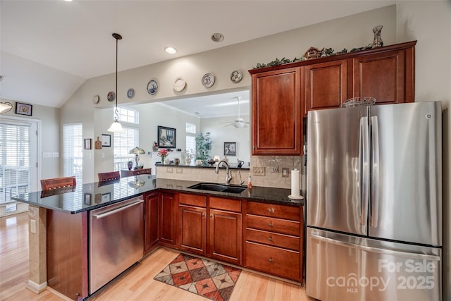 kitchen with sink, kitchen peninsula, stainless steel appliances, and dark stone counters