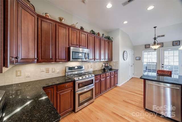 kitchen featuring stainless steel appliances, tasteful backsplash, lofted ceiling, dark stone counters, and light hardwood / wood-style flooring