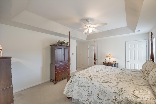 carpeted bedroom featuring a raised ceiling and ceiling fan