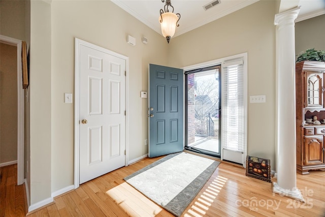 foyer featuring light wood-type flooring, ornate columns, and crown molding