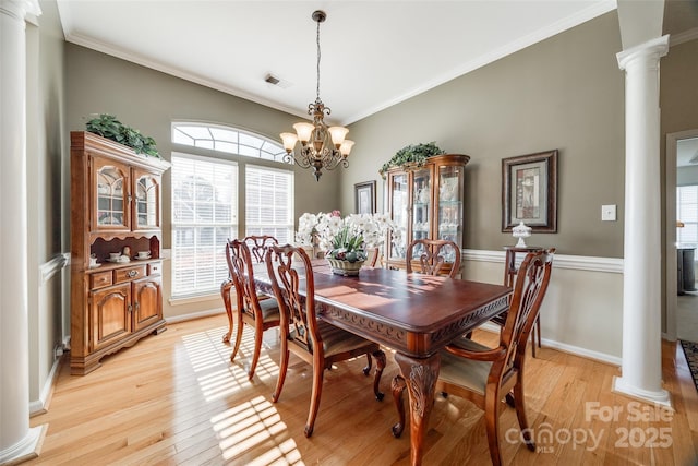 dining area featuring ornamental molding, ornate columns, a notable chandelier, and light wood-type flooring