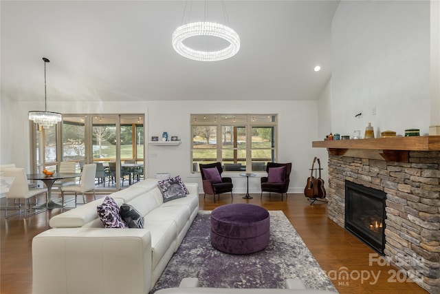 living room featuring dark hardwood / wood-style flooring, a wealth of natural light, an inviting chandelier, and a fireplace