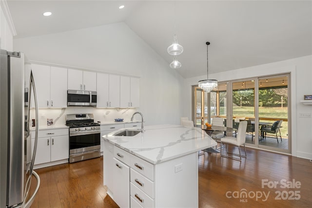 kitchen featuring appliances with stainless steel finishes, tasteful backsplash, white cabinetry, sink, and a center island with sink