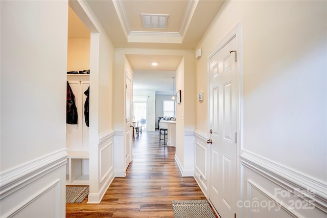 hallway featuring a tray ceiling, crown molding, and hardwood / wood-style flooring