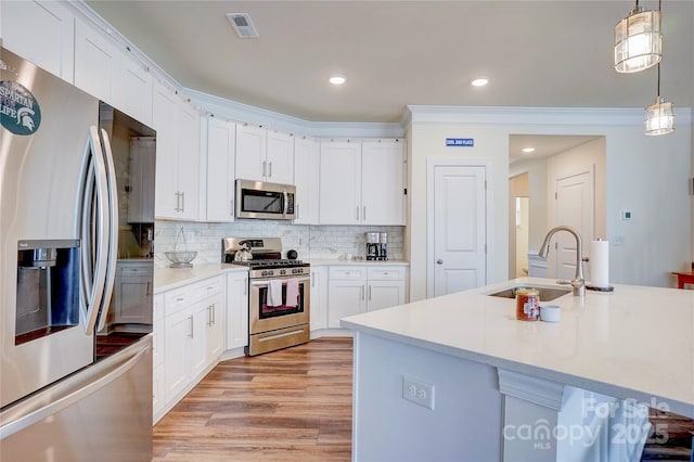 kitchen featuring hanging light fixtures, appliances with stainless steel finishes, sink, and white cabinetry