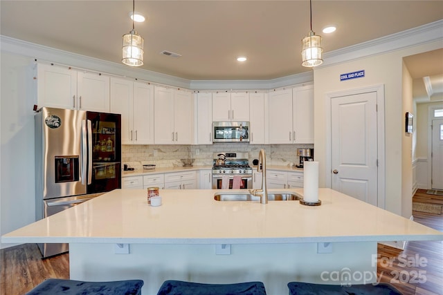 kitchen with sink, white cabinets, stainless steel appliances, and an island with sink