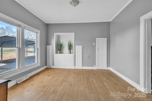 spare room with ornamental molding and light hardwood / wood-style floors